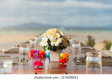 Flowers On An All Set Table For A Dinner Party With Beach Background.