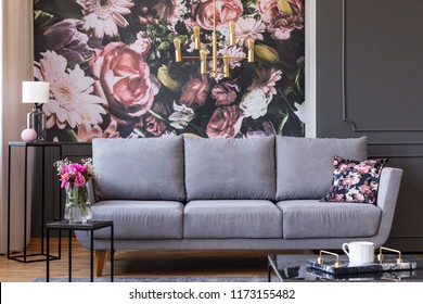 Flowers on black table and grey sofa in living room interior with lamp and wallpaper. Real photo - Shutterstock ID 1173155482