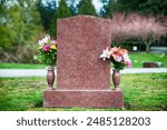 Flowers on a blank tombstone in natural surroundings.