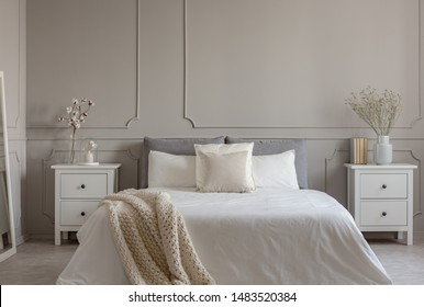 Flowers On White Wooden Nightstand Table In Luxury Bedroom Interior With King Size Bed