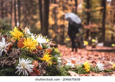 Blumen auf Grabstein. Enzentrierte Trauerfrau, die Blumen in Händen hält und auf dem Friedhof auf Grab steht. Respekt und letzter Abschied für Tote