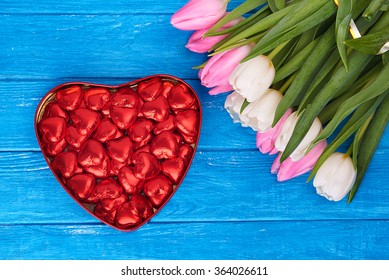 Flowers, Valentines Day And Holidays Concept - Close View At Red Tulips And Heart Shaped Chocolate Box On Wooden Turquoise Table