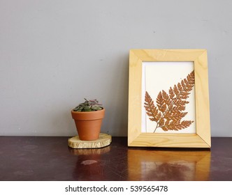 Flowers Vase And Wooden Picture Frame On Wooden Desktop