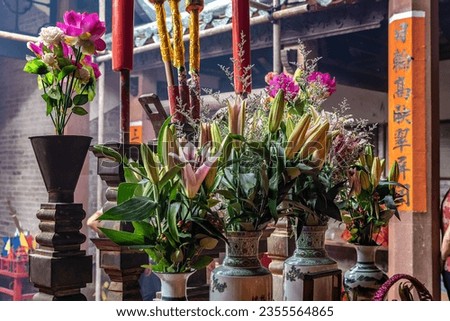 Flowers in vases on the temple altar in china. Votive offerings used in rituals to worship the deities. Translation: the sun is high and the mountains are green.