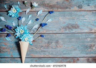 Flowers in a waffle cone on old blue wooden background