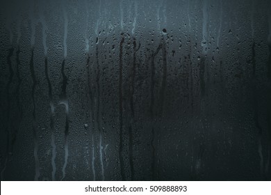 Flowing down water drops on glass