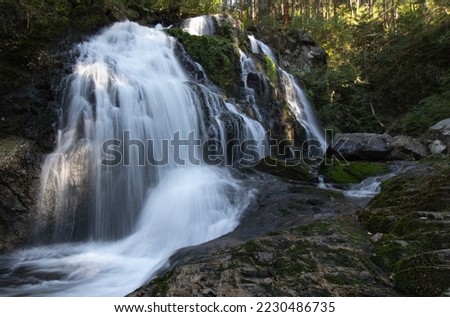 A flowing water fall scene with nicely textured rocks and sunlight poking through.  Steelhead Falls is located in Mission, British Columbia, Canada.