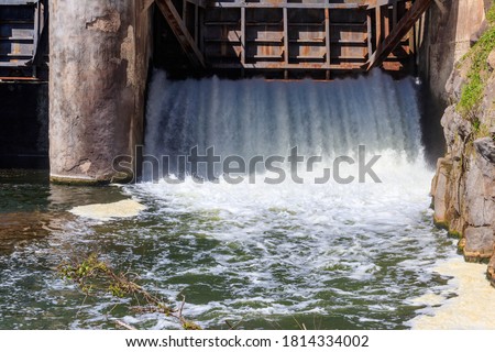 Flowing water with water spray from the open sluice gates of a small dam