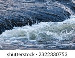 flowing water of a summer river with a small rapid waterfall at evening light, short or fast shutter speed