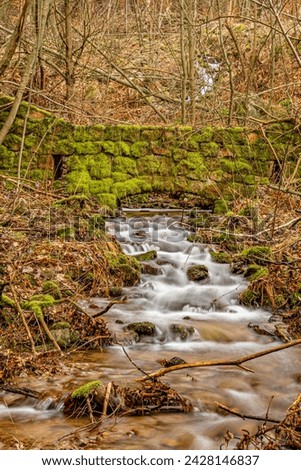flowing water under old mossy stony bridge