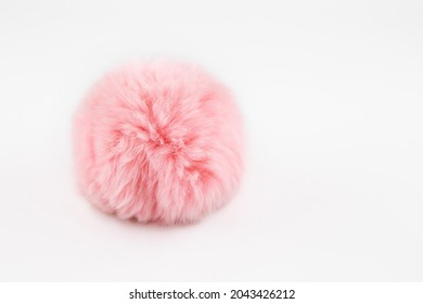 A fluffy ball of pink faux fur on a white background. Pompon. A toy for a cat. Decoration and decor of clothes. Eco-fur ball, soft and pleasant to the touch - Shutterstock ID 2043426212
