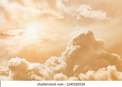 Fluffy clouds illuminated by the sun against a orange sunset sky (background, toned)