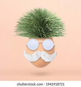 Fluffy creative Easter egg made of green grass, sunglasses and mustache on pastel pink background. Minimal spring concept. Flat lay.
