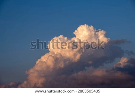 Fluffy cumulus cloud formation over coastal mountains and city skyline at sunset