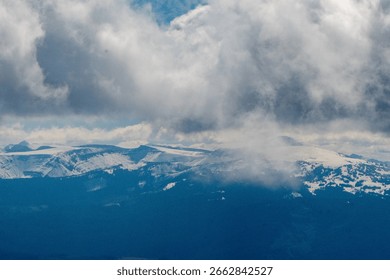 Fluffy cumulus clouds hover over the Teton Range, part of the Rocky Mountains near Grand Teton National Park