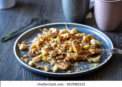 Fluffy, Gluten-free, Shredded Pancake / Kaiserschmarrn Served With Halvah Spread, Banana, Walnuts, And Grated Chocolate Placed On A Decorative Plate And Teacups At The Background