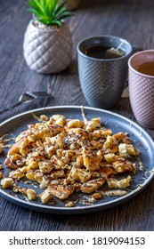 Fluffy, Gluten-free, Shredded Pancake / Kaiserschmarrn Served With Halvah Spread, Banana, Walnuts, And Grated Chocolate Placed On A Decorative Plate And Teacups At The Background