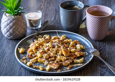 Fluffy, Gluten-free, Shredded Pancake / Kaiserschmarrn Served With Halvah Spread, Banana, Walnuts, And Grated Chocolate Placed On A Decorative Plate And Teacups At The Background