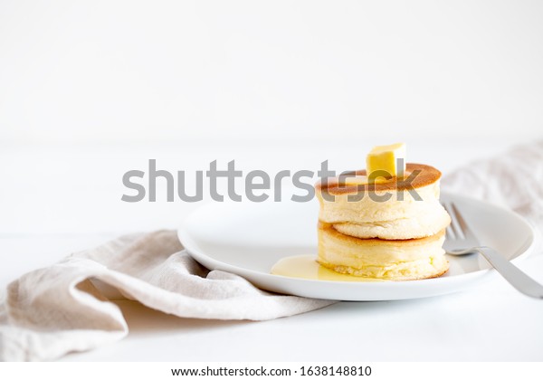 Fluffy\
Japan souffle pancakes, hotcakes with butter and maple syrup or\
honey sauces on light white background with copy space. Trendy\
asian food for breakfast. Horizontal\
orientation