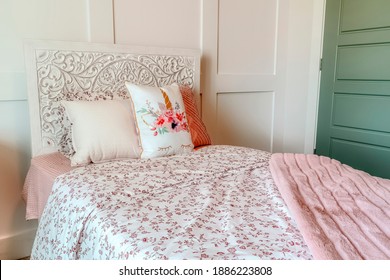 Fluffy Pillows Against Headboard Of Bed With Floral Bedsheet And Pink Blanket