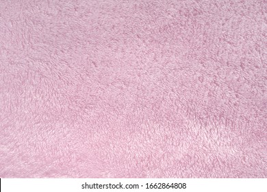 Fluffy pink synthetic fabric background. Soft plush pastel textile texture of winter clothing, baby toys, and home textiles. Rose delicate towel terry cloth. Plush fabric cozy plaid