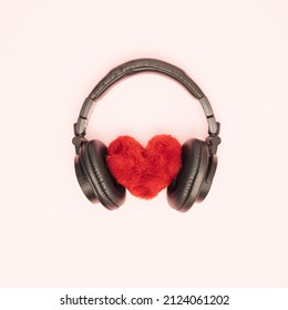 Fluffy soft heart with black headphones on white background. Feelings, love and emotions. Music and sound. Flat lay.