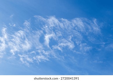 Fluffy, thin white clouds float in a clear blue southern African sky image for background use
