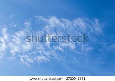 Fluffy, thin white clouds float in a clear blue southern African sky image for background use