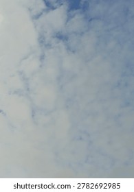 Fluffy white altocumulus clouds pattern spreading across a clear blue sky