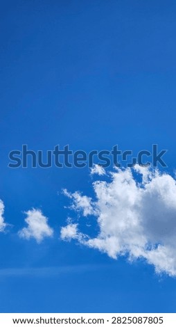 Fluffy white cloud on a bright blue sky background on a clear sunny day