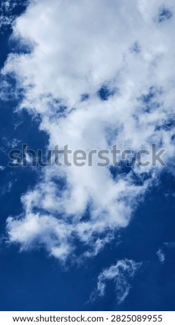 Fluffy white cloud on a bright blue sky background on a clear sunny day