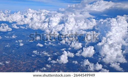 Fluffy white clouds appear soft against the blue sky as seen from the airplane window