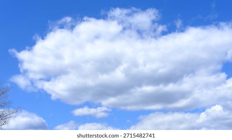 Fluffy white clouds float in a blue sky with sunlight illuminating the clouds and clear atmosphere during daytime with no visible objects or structures present