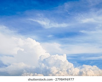 Fluffy white clouds float in a bright blue summer sky.