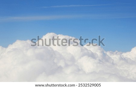 fluffy white cumulus clouds below and clear blue sky seen from a passenger airplane during daytime flight