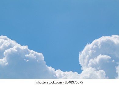 Fluffy white high clouds framing bright blue sky, cloudscape background. Skyscape natural heavenly scenery with copy space