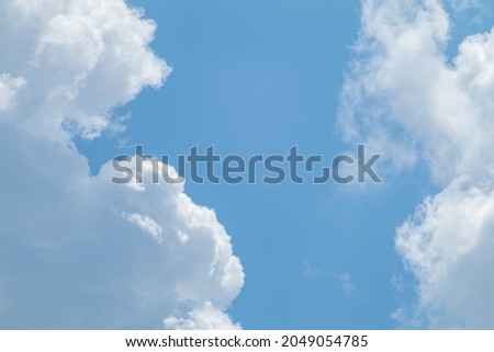 Fluffy white high clouds framing bright blue sky, cloudscape background. Skyscape natural heavenly scenery