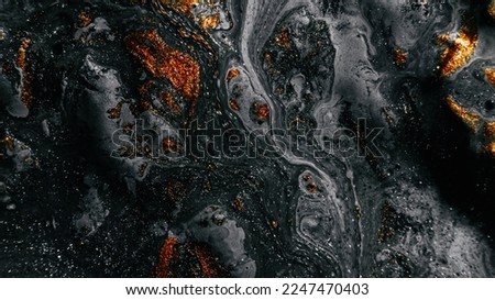 Fluid art. Glitter paint. Marble texture. Defocused shiny black gray gold color oil bubble ink blend wave dark abstract background.