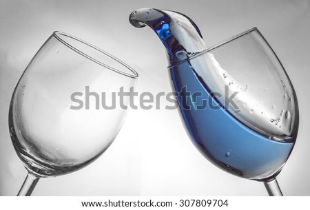 Fluid motion of coloured water in a wine glass with blownout highlights