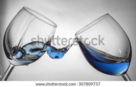 Fluid motion of coloured water in a wine glass with blownout highlights
