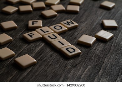 Fluid/flow affirmation spelt out using tiles on a timber surface
