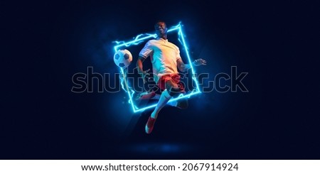 Fluorescence. Young man, professional football player in motion and action with ball isolated on dark background with neoned geometric figure. Concept of active lifestyle, health, sport, motivation