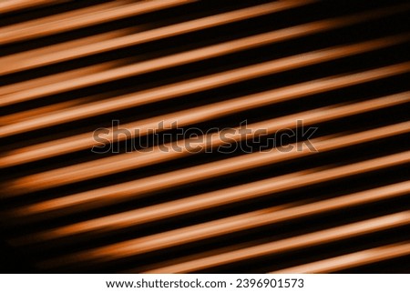Fluorescent background. Blur curved texture. Futuristic light. Defocused neon orange Peach Fuzz brown color diagonal stripes glow on dark ridged abstract overlay, trend color of 2024.