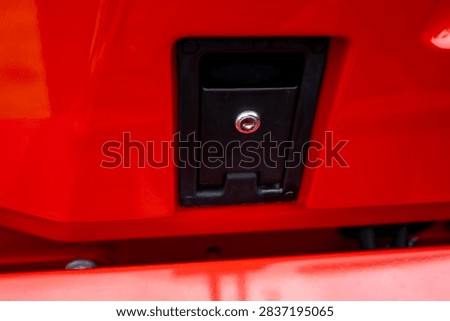 Flush mount black lockable latch handle with keyhole installed on red metal body panel of agricultural machinery or commercial vehicle.