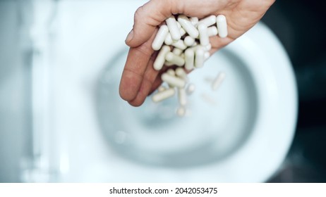 Flushing medical capsules into the toilet. Bad drug concept - Shutterstock ID 2042053475