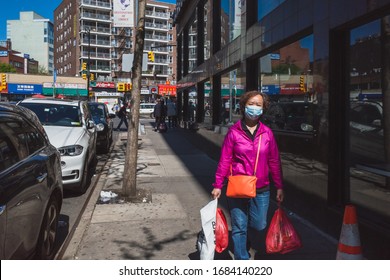 Flushing, New York City - April 24, 2019: Asian woman with face mask walking down street in Flushing Chinatown