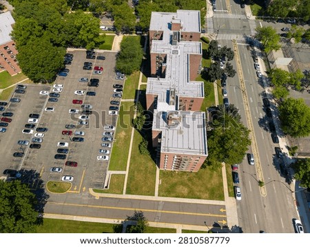 Flushing queens ny arial view showing multiple residential apartment buildings with their flat roofs. A sprawling parking lot filled with cars. A busy city street