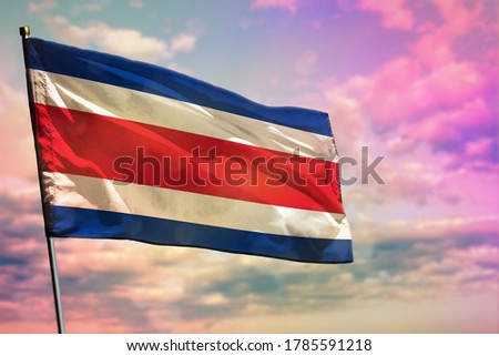 Fluttering Costa Rica flag on colorful cloudy sky background. Costa Rica prospering concept.
