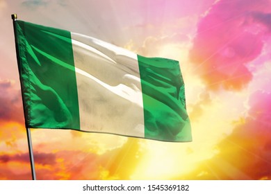 Fluttering Nigeria Flag On Beautiful Colorful Sunset Or Sunrise Background. Nigeria Success And Happiness Concept.