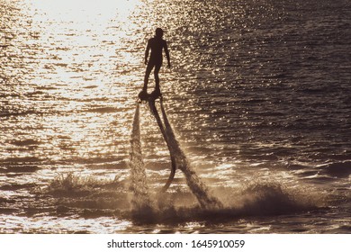 Fly Boarding Silhouette Extreme Water Sports In Ras Al Khaimah, United Arab Emirates Near Dubai At Sunset Having Fun On The Water. Recreation And Sports Concepts.